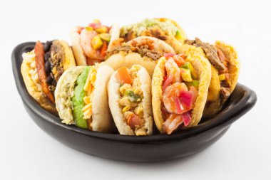 Beyaz arka plan üzerinde siyah bir seramik tabak arepas çeşitli dolguları ile servis