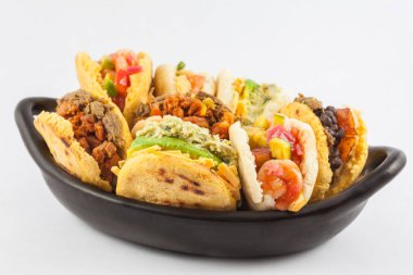Beyaz arka plan üzerinde siyah bir seramik tabak arepas çeşitli dolguları ile servis