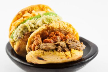 Beyaz arka plan üzerinde siyah bir seramik tabak arepas iki farklı dolguları ile servis