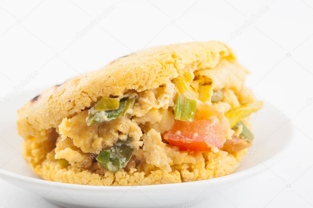 Arepas filled with scrambled eggs served in a white dish on white background