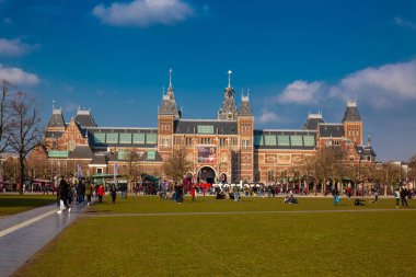 Amsterdam, Hollanda - Mart, 2018: National Museum Amsterdam yanında ünlü Müze Meydanı'nda bir güneşli erken bahar günü zevk insanlar