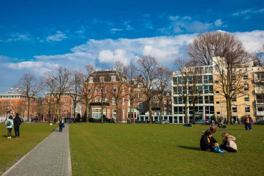 Amsterdam, Hollanda - Mart, 2018: National Museum Amsterdam yanında ünlü Müze Meydanı'nda bir güneşli erken bahar günü zevk insanlar