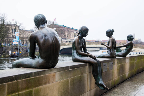 БЕРЛИН, ГЕРМАНИЯ - Март 2018 года: Скульптура "Три девушки и мальчик", созданная Вильфридом Фитценрайтером, расположенным на берегах реки Шпрее в холодном дождливом конце зимнего дня
