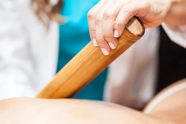 Läkare som utför en bambu terapi behandling på en ung kvinnlig patient tillbaka — Stockfoto