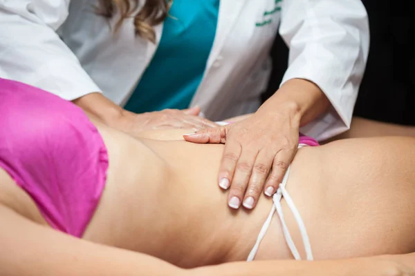 Läkare utför en buken massage på en ung kvinnlig patient — Stockfoto