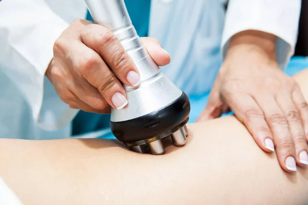 Médico realizando un tratamiento de radiofrecuencia en una pierna de paciente joven — Foto de Stock