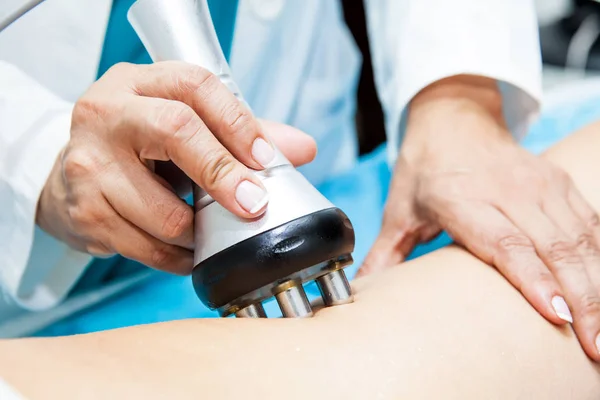 Médico realizando un tratamiento de radiofrecuencia en una pierna de paciente joven — Foto de Stock