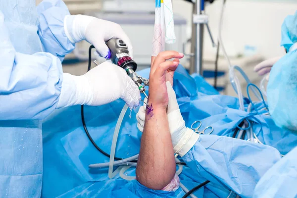 Grupo de cirujanos ortopédicos que realizan una artroscopia de muñeca en un paciente masculino —  Fotos de Stock