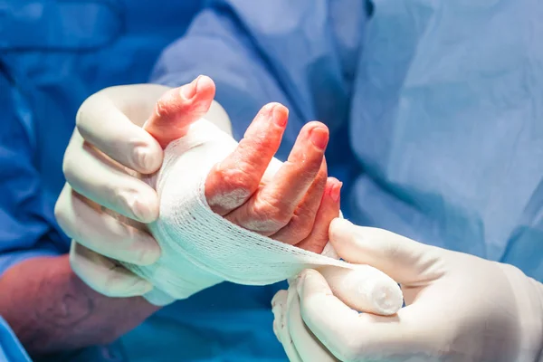 Kirurgen bandage patientens hand i slutet av operationen — Stockfoto