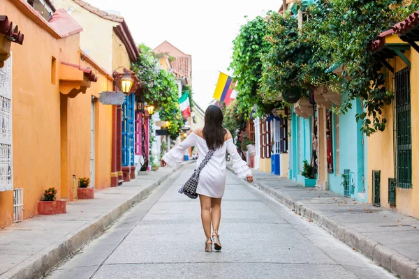 Mooie vrouw op witte jurk lopen alleen op de kleurrijke straten van de koloniale ommuurde stad van Cartagena de Indias — Stockfoto