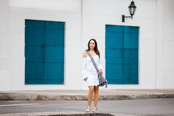 Schöne Frau im weißen Kleid, die allein durch die Straßen der kolonialen ummauerten Stadt Cartagena de Indias geht — Stockfoto