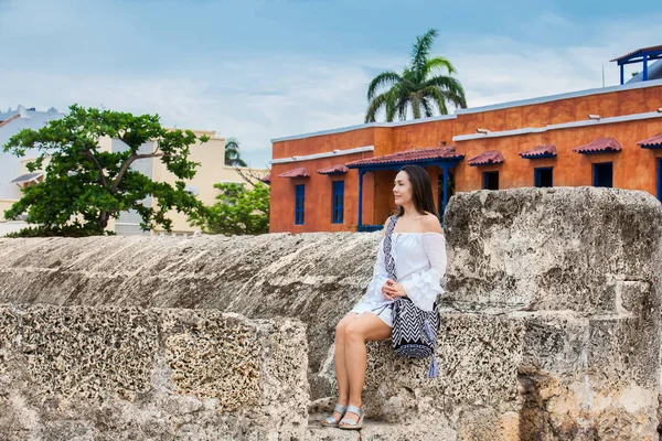 Beyaz elbise üzerinde güzel kadın tek başına duvarları Cartagena de Indias sömürge kenti çevreleyen oturan — Stok fotoğraf