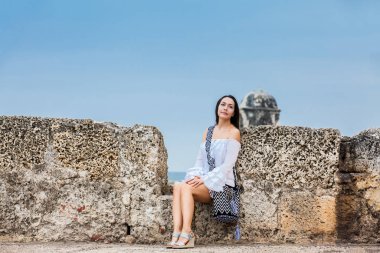 Beyaz elbise üzerinde güzel kadın tek başına duvarları Cartagena de Indias sömürge kenti çevreleyen oturan