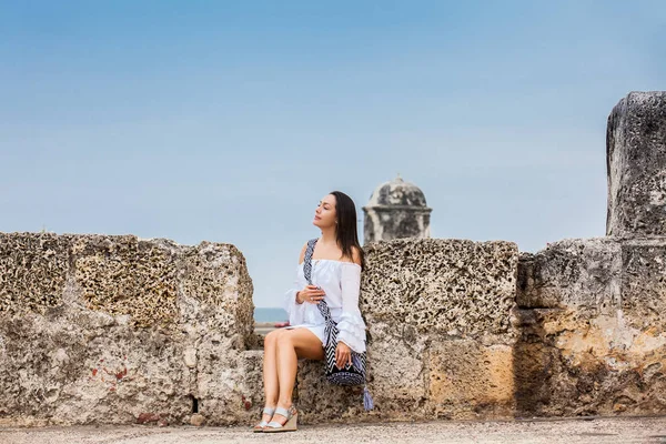 Mooie vrouw op witte jurk zitten alleen op de muren rond de koloniale stad Cartagena de Indias — Stockfoto