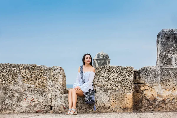 Beyaz elbise üzerinde güzel kadın tek başına duvarları Cartagena de Indias sömürge kenti çevreleyen oturan