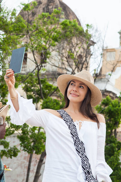 Красивая молодая женщина примеряет шляпы, чтобы купить один из уличных торговцев в Картахене де Индиас стены города
