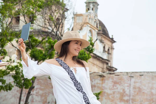 Hermosa joven probándose sombreros para comprar uno a un vendedor ambulante en Cartagena de Indias ciudad amurallada — Foto de Stock