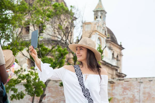 Mooie jonge vrouw proberen op hoeden om een te kopen van een straat verkoper in Cartagena de Indias ommuurde stad — Stockfoto