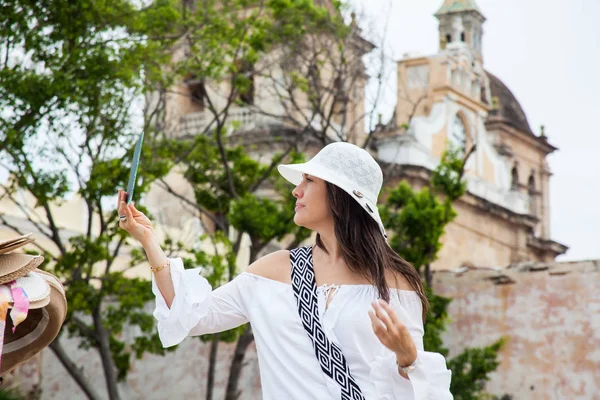 美しい若い女性は、カルタヘナ・デ・インディアの城壁都市の露天商から1つを購入するために帽子を試みる — ストック写真