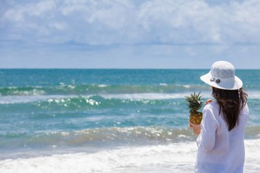Güneşli bir günde tropik bir plajda tropik bir içki içen bir kadın.