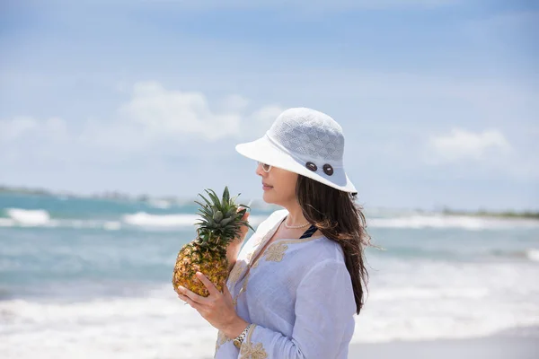 Woman having a tropical drink at a paradisiac tropical beach in a beautiful sunny day