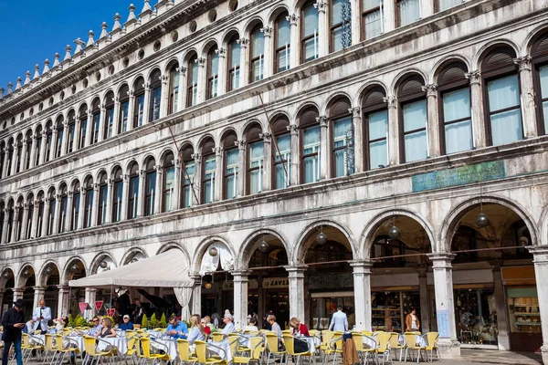 Restauranter og turister på den berømte Saint Mark Square i Venedig i en smuk solrig tidlig forårsdag - Stock-foto