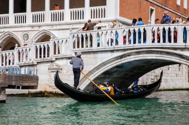 Venedik'teki Büyük Kanal'da Doge Sarayı'nın önünde bir gondolda yelken süren turistler