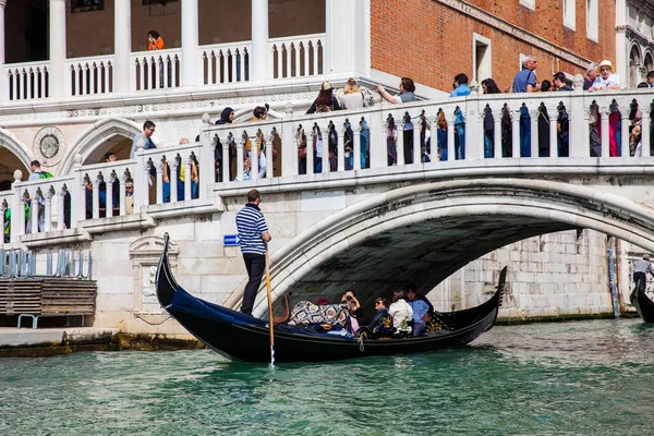 Venedik'teki Büyük Kanal'da Doge Sarayı'nın önünde bir gondolda yelken süren turistler