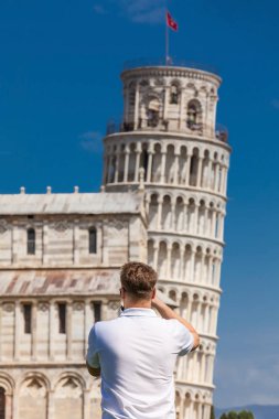 Genç erkek turist Pisa ünlü Eğik Kulesi fotoğraf çekmek