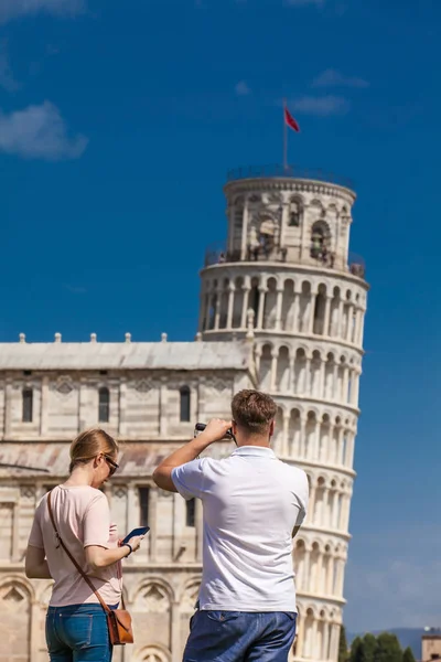 Jeune couple de touristes prenant des photos de la célèbre Tour penchée de Pise — Photo