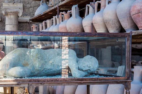 Plaster cast of an inhabitant and artifacts in the Forum Granary of the ancient city of Pompeii — Stock Photo, Image