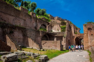 Roma'daki antik Roma Forumu'nda Via Nova'da kemerin yanından yürüyen turistler