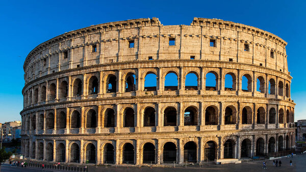 ROME, ITALY - APRIL, 2018: Tourists visiting the famous Colosseum under the beautiful light of the golden hour in Rome