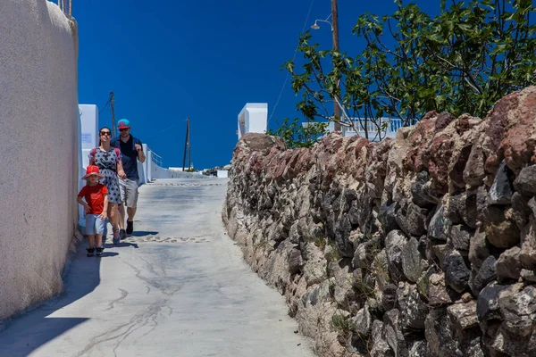 Los turistas familia caminando por los hermosos callejones de la ciudad de Fira en la isla de Santorini en un hermoso día de primavera — Foto de Stock