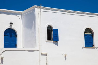 Santorini Adası'nda beyaz duvarlar üzerinde geleneksel güzel mavi pencereler