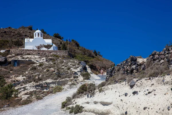 Mujer joven caminando por el sendero entre Fira y Oia pasando por la Iglesia de San Marcos en la isla de Santorini — Foto de Stock