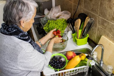 Senior woman at home washing and disinfecting fruits and vegetables. Senior woman disinfecting fruits and vegetables purchased during the COVID-19 pandemic