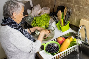 Senior woman disinfecting fruits and vegetables purchased during the COVID-19 pandemic clipart