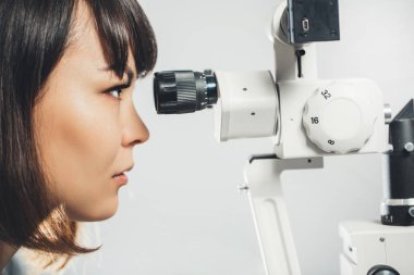 göz doktoru stajyer görünüyor göz kontrol etmeyi mercek aparatı. Oftalmoloji, hastane, tıbbi muayene.