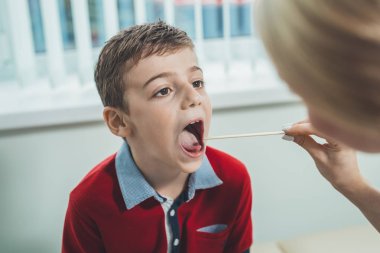 oğlan var strep boğaz. Çocuk oğlu doktor, çocuğun boğazını inceliyor. Çocuk hastalıkları, tıbbi muayene.