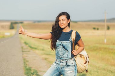 Bir sırt çantası ile esmer kız otostop araba yakalar. kavram-seyahat, Macera, özgürlük.