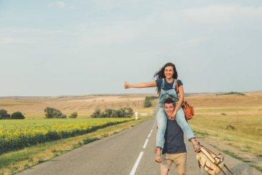 Otostop. Öğrenci hipster arkadaşının erkek omuzlarında oturur. Çok iyi. Kavram - macera, özgür, özgürlük.