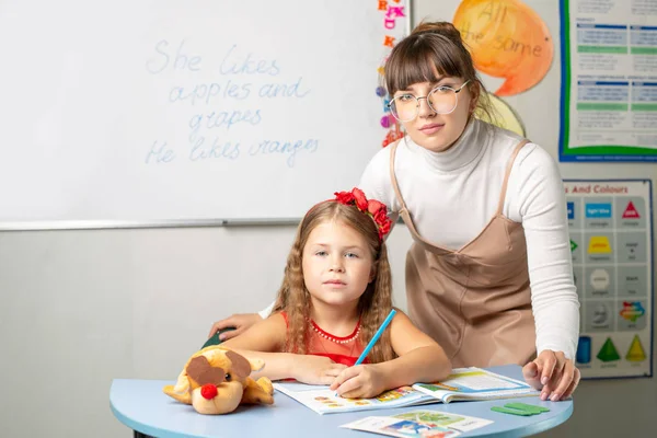 English tutor helps a girl to do her homework. Preparation for exams in English. — Stock Image English Tutor Helps Girl Her Homework Preparation Exams English Stock Image