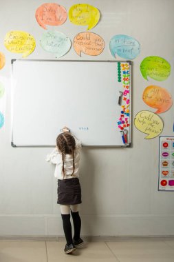 Little student meets the blackboard lesson. The teacher checks the homework. clipart