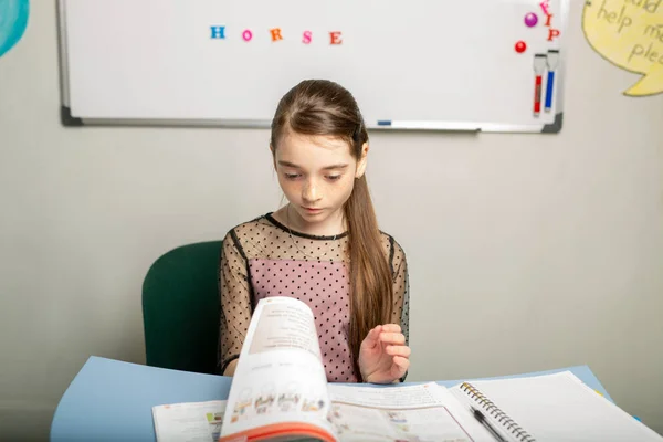 girl learns English through the textbook. Concept - independent study of a foreign language.