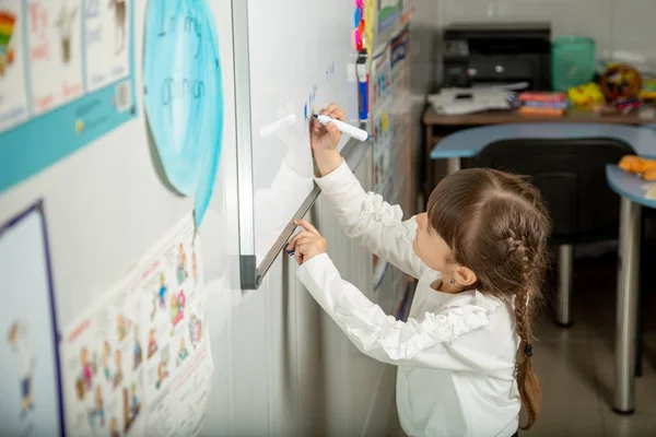 Little student meets the blackboard lesson. The teacher checks the homework. — Stock Image Little Student Meets Blackboard Lesson Teacher Checks Homework Royalty Free Stock Images