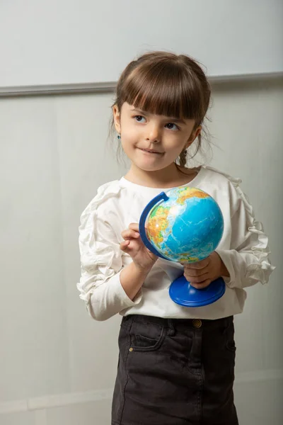 Little student is holding a globe. — Stock Image Little Student Holding Globe Stock Photo