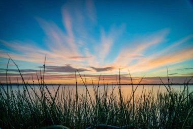 Mavi gökyüzü ve Avustralya'da bir göl üzerinde turuncu günbatımı