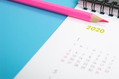 kırmızı kalem ve takvim üzerinde mavi arka plan