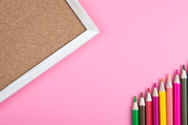 renkli kalemler ve kırmızı zemin üzerine mantar pano